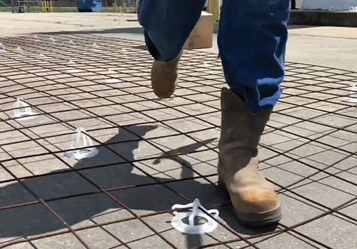 Installer shown walking over the rebar supported by Mesh-ups in a concrete driveway installation.